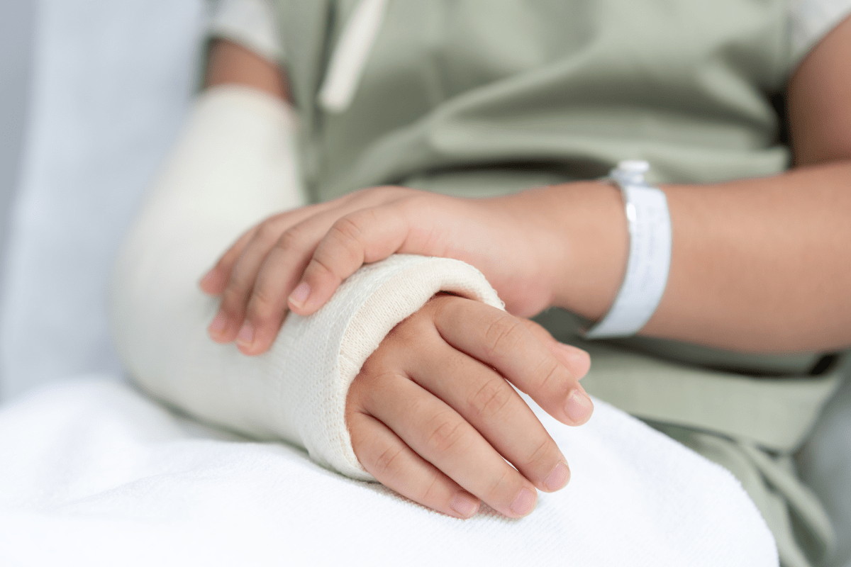 A close-up of a person’s hands, one of which is wrapped in a white bandage.