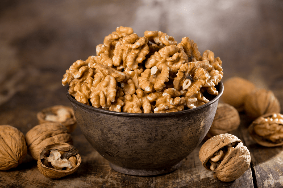 A bowl of walnuts with some cracked open.