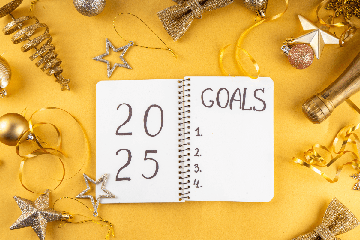 Notebook with '2025 Goals' written on a festive gold background decorated with ornaments and ribbons.