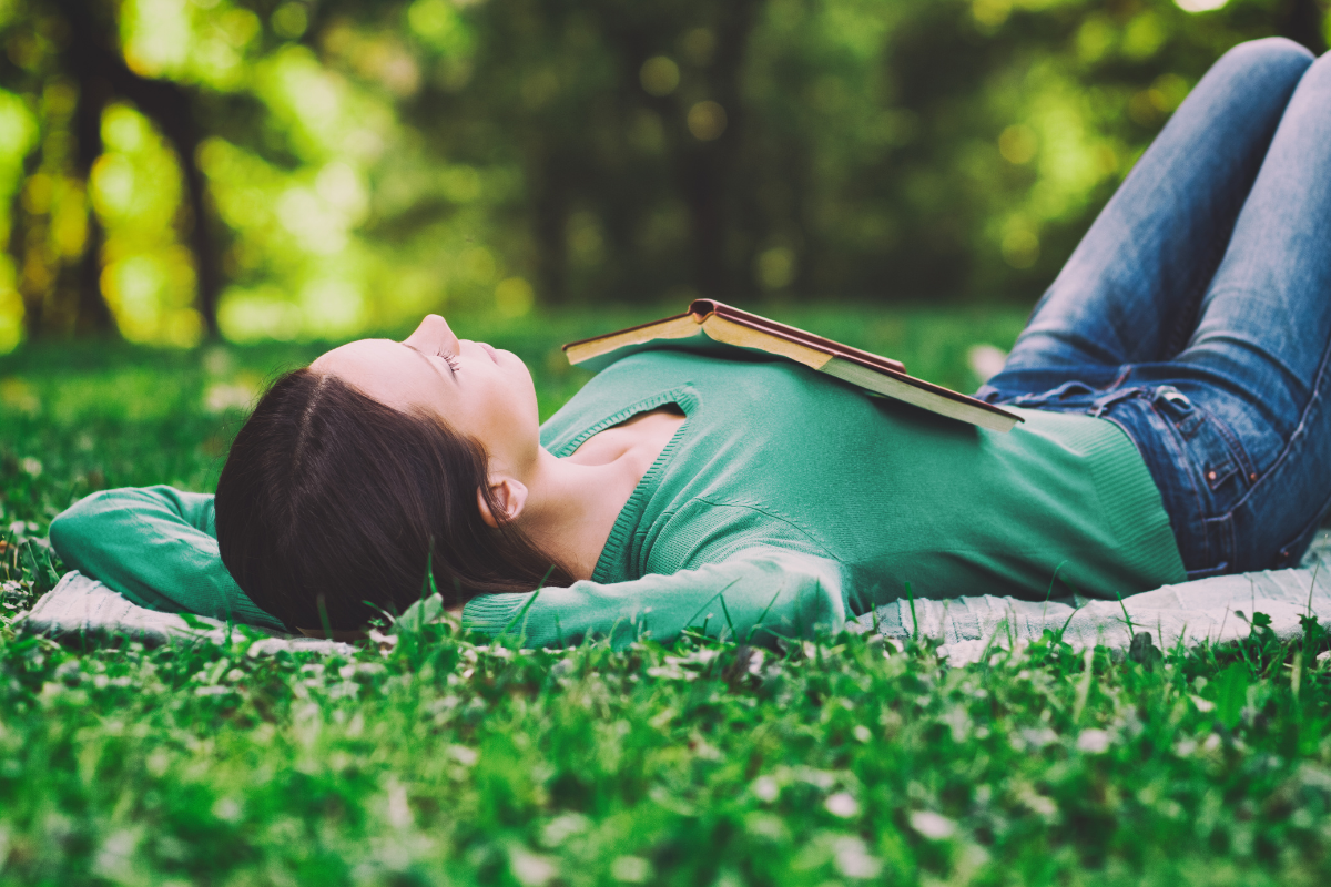 Woman relaxing on the grass with a book.