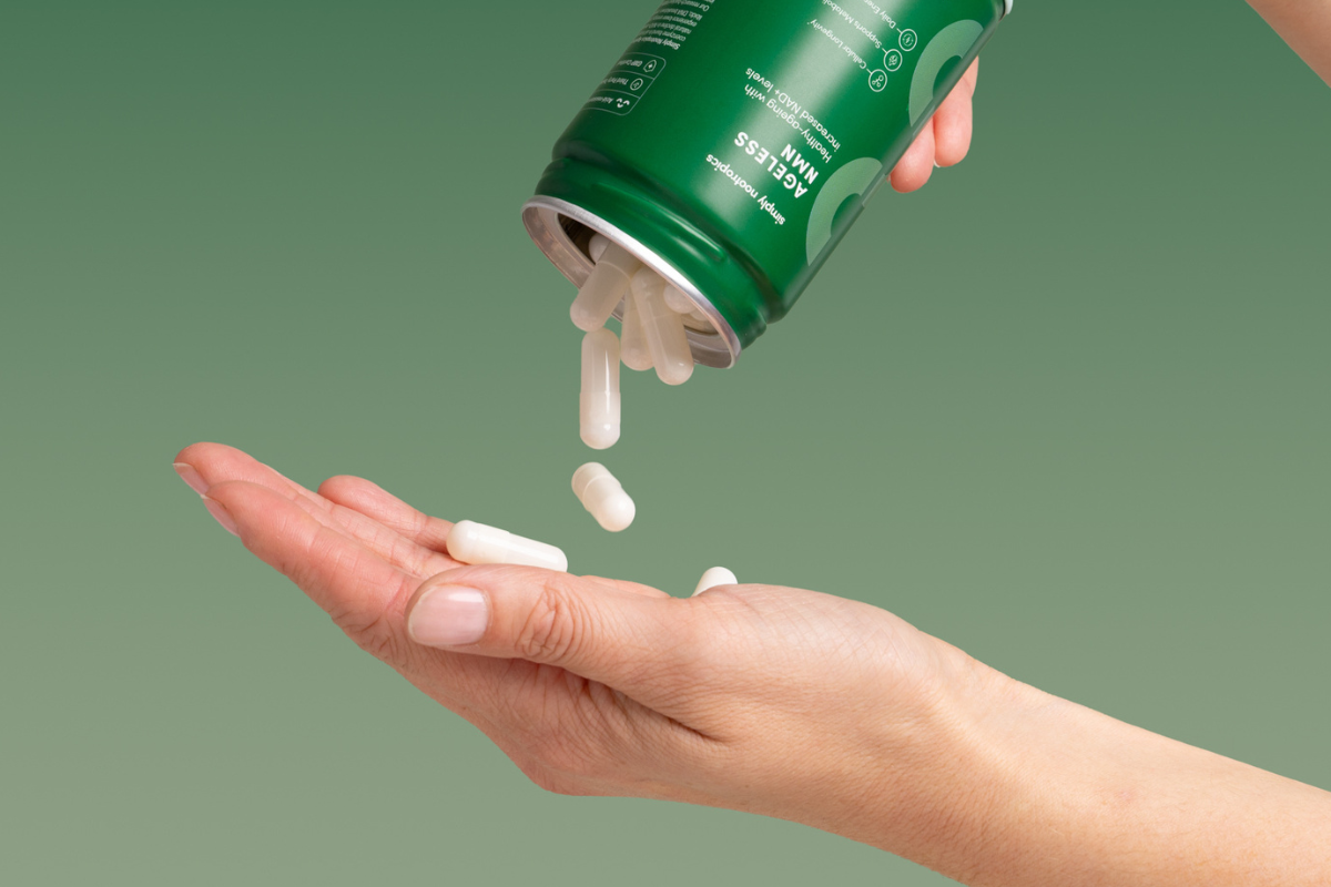 Capsules being poured from a supplement bottle into a hand.